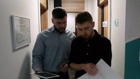 Männliche Kollegen besprechen die Arbeitsfragen, die im Korridor des Bürogebäudes gehen stock footage Männliche Kollegen besprechen die Arbeitsfragen, die im Korridor des Bürogebäudes gehen stock footage