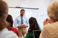 Männlicher Lehrer, der auf Studenten an der Erwachsenenbildungsklasse hört lizenzfreies stockfoto Männlicher Lehrer, der auf Studenten an der Erwachsenenbildungsklasse hört lizenzfreies stockfoto