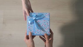 Mäns händer ger en ask med en gåva till en kvinna Mäns händer ger en ask med en gåva till en kvinna