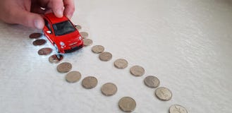 Mężczyzna rusza się z jego palca Fiat 500 abarth czerwoną zabawką na drogi linii robić jeden syklu Izraelickie monety w zdjęcia stock Mężczyzna rusza się z jego palca Fiat 500 abarth czerwoną zabawką na drogi linii robić jeden syklu Izraelickie monety w zdjęcia stock