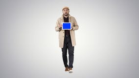 Młodego człowieka odprowadzenie opowiada cyfrową pastylkę z błękitnego ekranu mockup na gradientowym tle i pokazuje, fotografia stock Młodego człowieka odprowadzenie opowiada cyfrową pastylkę z błękitnego ekranu mockup na gradientowym tle i pokazuje, fotografia stock