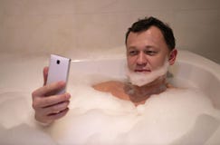 Młody uśmiechnięty mężczyzna siedzi łazienkę robi broda wp8lywy selfie fotografia stock Młody uśmiechnięty mężczyzna siedzi łazienkę robi broda wp8lywy selfie fotografia stock