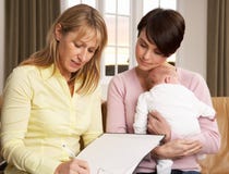 Mère avec la chéri parlant avec le visiteur de santé photo stock Mère avec la chéri parlant avec le visiteur de santé photo stock