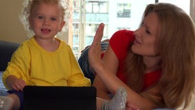 Mère de sourire et sa fille mignonne d'enfant en bas âge à l'aide du comprimé à la maison banque de vidéos Mère de sourire et sa fille mignonne d'enfant en bas âge à l'aide du comprimé à la maison banque de vidéos