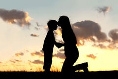 Mère embrassant affectueusement le petit enfant au coucher du soleil Mère embrassant affectueusement le petit enfant au coucher du soleil