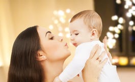 Mère embrassant le bébé au-dessus des lumières de Noël image libre de droits Mère embrassant le bébé au-dessus des lumières de Noël image libre de droits