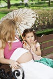 Mère et fille s'asseyant sur un banc de parc photographie stock Mère et fille s'asseyant sur un banc de parc photographie stock