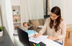 Mère heureuse avec le bébé et papiers fonctionnant à la maison Photographie stock libre de droits Mère heureuse avec le bébé et papiers fonctionnant à la maison Photographie stock libre de droits