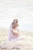 Mère s'asseyant sur la plage avec une belle petite fille Enfant étreignant, souriant, riant, jour d'été Enfance heureux g insouci images stock Mère s'asseyant sur la plage avec une belle petite fille Enfant étreignant, souriant, riant, jour d'été Enfance heureux g insouci images stock