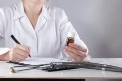 Médico da jovem mulher com tratamento de prescrição do estetoscópio ao paciente Receita fêmea da escrita do doutor na prancheta d foto de stock Médico da jovem mulher com tratamento de prescrição do estetoscópio ao paciente Receita fêmea da escrita do doutor na prancheta d foto de stock