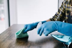 Ménage de mari et concept de nettoyage, jeune homme heureux essuyant la poussière utilisant un pulvérisateur et un chiffon tout e images stock Ménage de mari et concept de nettoyage, jeune homme heureux essuyant la poussière utilisant un pulvérisateur et un chiffon tout e images stock