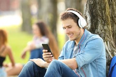 Música de escuta do estudante com fones de ouvido em um parque fotos de stock Música de escuta do estudante com fones de ouvido em um parque fotos de stock