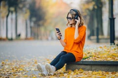 Música que escucha en auriculares, estilo urbano, adolescencia elegante de la chica joven linda del inconformista que se sienta e imagen de archivo libre de regalías Música que escucha en auriculares, estilo urbano, adolescencia elegante de la chica joven linda del inconformista que se sienta e imagen de archivo libre de regalías