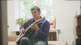 músico de sexo masculino que toca la guitarra acústica hombre que juega el vídeo de la cámara lenta de la guitarra acústica en el almacen de metraje de vídeo músico de sexo masculino que toca la guitarra acústica hombre que juega el vídeo de la cámara lenta de la guitarra acústica en el almacen de metraje de vídeo