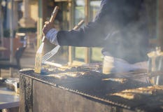 Mężczyzna gotuje śledzia na grillu na rynku obraz stock Mężczyzna gotuje śledzia na grillu na rynku obraz stock