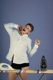 Mężczyzna i kobiet ` s odpowiedzialność Zmęczony mężczyzna rozciąganie, ziewanie przy prasowanie deską z żelazami i zdjęcie stock Mężczyzna i kobiet ` s odpowiedzialność Zmęczony mężczyzna rozciąganie, ziewanie przy prasowanie deską z żelazami i zdjęcie stock