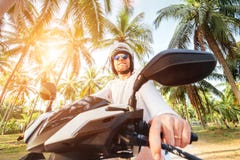 Mężczyzna jedzie motocykl pod drzewko palmowe kąta obiektywu szerokim strzałem w bezpiecznym hełmie fotografia royalty free Mężczyzna jedzie motocykl pod drzewko palmowe kąta obiektywu szerokim strzałem w bezpiecznym hełmie fotografia royalty free