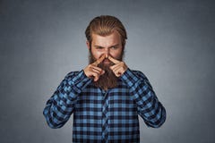 Mężczyzna nękań nosa spojrzenia z obmierzłością coś śmierdzą złego odór fotografia stock Mężczyzna nękań nosa spojrzenia z obmierzłością coś śmierdzą złego odór fotografia stock