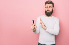 Mężczyzna trzyma razer w jego ręce Jest przyglądający ja z obmierzłością Odizolowywającą na różowym tle fotografia stock Mężczyzna trzyma razer w jego ręce Jest przyglądający ja z obmierzłością Odizolowywającą na różowym tle fotografia stock