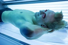 Mężczyzna w solarium cieszy się sunbathing na skórniczym łóżku Obraz Stock Mężczyzna w solarium cieszy się sunbathing na skórniczym łóżku Obraz Stock