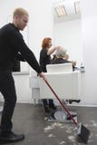 Mężczyzna Zamiata Podczas gdy fryzjer Daje ostrzyżeniu Starsza kobieta zdjęcie stock Mężczyzna Zamiata Podczas gdy fryzjer Daje ostrzyżeniu Starsza kobieta zdjęcie stock