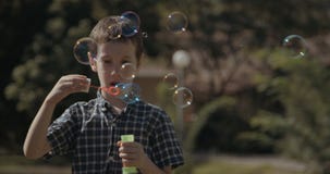 Młoda chłopiec dmucha mydlanych bąble outdoors zdjęcie wideo Młoda chłopiec dmucha mydlanych bąble outdoors zdjęcie wideo