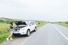 Młoda dorosła kobieta stoi blisko łamanego samochodu na autostradzie i talkin fotografia stock Młoda dorosła kobieta stoi blisko łamanego samochodu na autostradzie i talkin fotografia stock