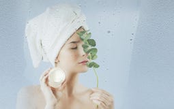Młoda dziewczyna po brać skąpanie używa nawilżania ciało twarzy śmietankę na błękitnym tle i Pojęcie skóry opieka fotografia stock Młoda dziewczyna po brać skąpanie używa nawilżania ciało twarzy śmietankę na błękitnym tle i Pojęcie skóry opieka fotografia stock