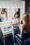 Młoda fachowa visagiste mienia paleta stosuje eyeshadow Kaukaski kobieta model w piękno sklepie zdjęcie stock Młoda fachowa visagiste mienia paleta stosuje eyeshadow Kaukaski kobieta model w piękno sklepie zdjęcie stock