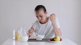 Młoda kobieta je cornflakes z mlekiem dla śniadania z apetytem zbiory Młoda kobieta je cornflakes z mlekiem dla śniadania z apetytem zbiory