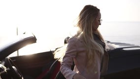 Młoda kobieta kierowca w beżowej skórzanej kurtce z długie włosy i eleganckimi okularami przeciwsłonecznymi otwiera drzwi jej kab zbiory wideo Młoda kobieta kierowca w beżowej skórzanej kurtce z długie włosy i eleganckimi okularami przeciwsłonecznymi otwiera drzwi jej kab zbiory wideo