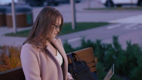 Młoda kobieta na ławce w wieczór parku pracuje online na laptopie zbiory wideo Młoda kobieta na ławce w wieczór parku pracuje online na laptopie zbiory wideo