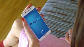 Młoda kobieta trzyma telefon komórkowego z ładować PayPal wiszącą ozdobę app Konceptualna artykułu wstępnego 4K klamerka zdjęcie wideo Młoda kobieta trzyma telefon komórkowego z ładować PayPal wiszącą ozdobę app Konceptualna artykułu wstępnego 4K klamerka zdjęcie wideo
