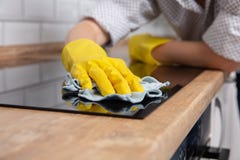Młoda kobieta wręcza czyścić nowożytnego czarnego indukcji hob łachmanem, sprzątanie obrazy stock Młoda kobieta wręcza czyścić nowożytnego czarnego indukcji hob łachmanem, sprzątanie obrazy stock