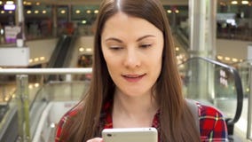 Młoda piękna kobiety pozycja w zakupy centrum handlowego ono uśmiecha się Używać jej smartphone, opowiada z przyjaciółmi zbiory wideo Młoda piękna kobiety pozycja w zakupy centrum handlowego ono uśmiecha się Używać jej smartphone, opowiada z przyjaciółmi zbiory wideo