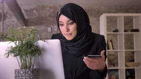 Młoda piękna muzułmańska dziewczyna w hijab ogląda w laptopie i trzyma kredytową kartę w biurze, pracy pojęcie, biznes zdjęcie wideo Młoda piękna muzułmańska dziewczyna w hijab ogląda w laptopie i trzyma kredytową kartę w biurze, pracy pojęcie, biznes zdjęcie wideo