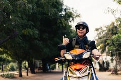 Młoda szczęśliwa, przystojna męska motocyklista jazda na motocyklu daje i obraz royalty free Młoda szczęśliwa, przystojna męska motocyklista jazda na motocyklu daje i obraz royalty free