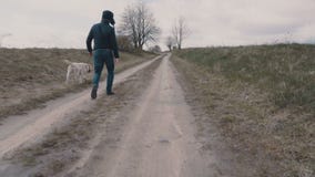 Młodego człowieka odprowadzenie z jego psem wzdłuż drogi gruntowej zdjęcie wideo Młodego człowieka odprowadzenie z jego psem wzdłuż drogi gruntowej zdjęcie wideo