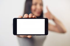 Młodej dziewczyny kobieta trzyma smartphone z pustym bielu ekranem horizontally przed ona i ono uśmiecha się zdjęcia royalty free Młodej dziewczyny kobieta trzyma smartphone z pustym bielu ekranem horizontally przed ona i ono uśmiecha się zdjęcia royalty free