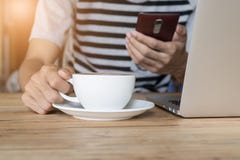 Młody człowiek pracuje przy sklep z kawą używać telefon co laptop i obraz royalty free Młody człowiek pracuje przy sklep z kawą używać telefon co laptop i obraz royalty free