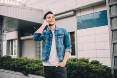 Młody człowiek stoi outdoors, opowiadający na telefonie obraz stock Młody człowiek stoi outdoors, opowiadający na telefonie obraz stock