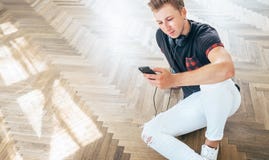 Młody człowiek używa jego smartphone z hełmofonami, słucha muzykę obrazy royalty free Młody człowiek używa jego smartphone z hełmofonami, słucha muzykę obrazy royalty free
