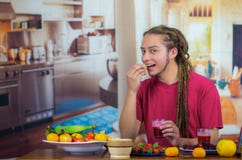 Młody człowiek z strachami cieszy się zdrowego śniadanie, je owoc, pije smoothie i ono uśmiecha się, domowy kuchenny tło Fotografia Royalty Free Młody człowiek z strachami cieszy się zdrowego śniadanie, je owoc, pije smoothie i ono uśmiecha się, domowy kuchenny tło Fotografia Royalty Free