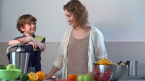 Młody Kaukaski matki i dziecka Domowej roboty Świeży sok pomarańczowy w kuchni z Elektrycznym Juicer zdjęcie wideo Młody Kaukaski matki i dziecka Domowej roboty Świeży sok pomarańczowy w kuchni z Elektrycznym Juicer zdjęcie wideo