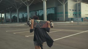 Młody piękny modniś kobiety odprowadzenie na ulicie i nieść dalej ręki jeździć na deskorolce lub longboard zbiory Młody piękny modniś kobiety odprowadzenie na ulicie i nieść dalej ręki jeździć na deskorolce lub longboard zbiory