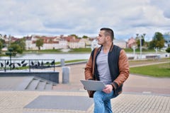 Młody pomyślny freelancer w skórzanej kurtce pracuje na stree zdjęcia stock Młody pomyślny freelancer w skórzanej kurtce pracuje na stree zdjęcia stock