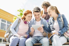Młodzi ucznie używa cyfrową pastylkę przy szkoła wyższa kampusem zdjęcie stock Młodzi ucznie używa cyfrową pastylkę przy szkoła wyższa kampusem zdjęcie stock