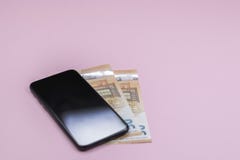 N?rbild av den smarta telefonen med pengar p? en rosa bakgrund royaltyfri fotografi N?rbild av den smarta telefonen med pengar p? en rosa bakgrund royaltyfri fotografi