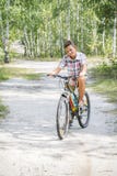 N the summer, in the forest, a boy rides a bike on the road. stock photography N the summer, in the forest, a boy rides a bike on the road. stock photography