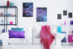 Nahaufnahme der weißen bequemen Couch mit rosa Decke und den purpurroten und blauen Kissen im modernen Wohnzimmerinnenraum, wirkl lizenzfreie stockfotos Nahaufnahme der weißen bequemen Couch mit rosa Decke und den purpurroten und blauen Kissen im modernen Wohnzimmerinnenraum, wirkl lizenzfreie stockfotos